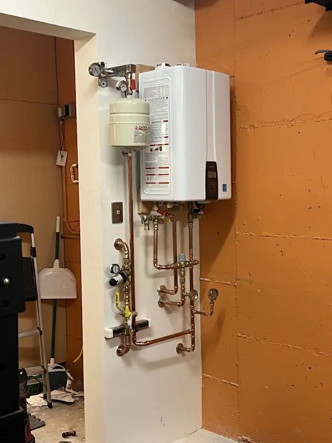 Plumbing technician inspecting water heater connections in Ravena